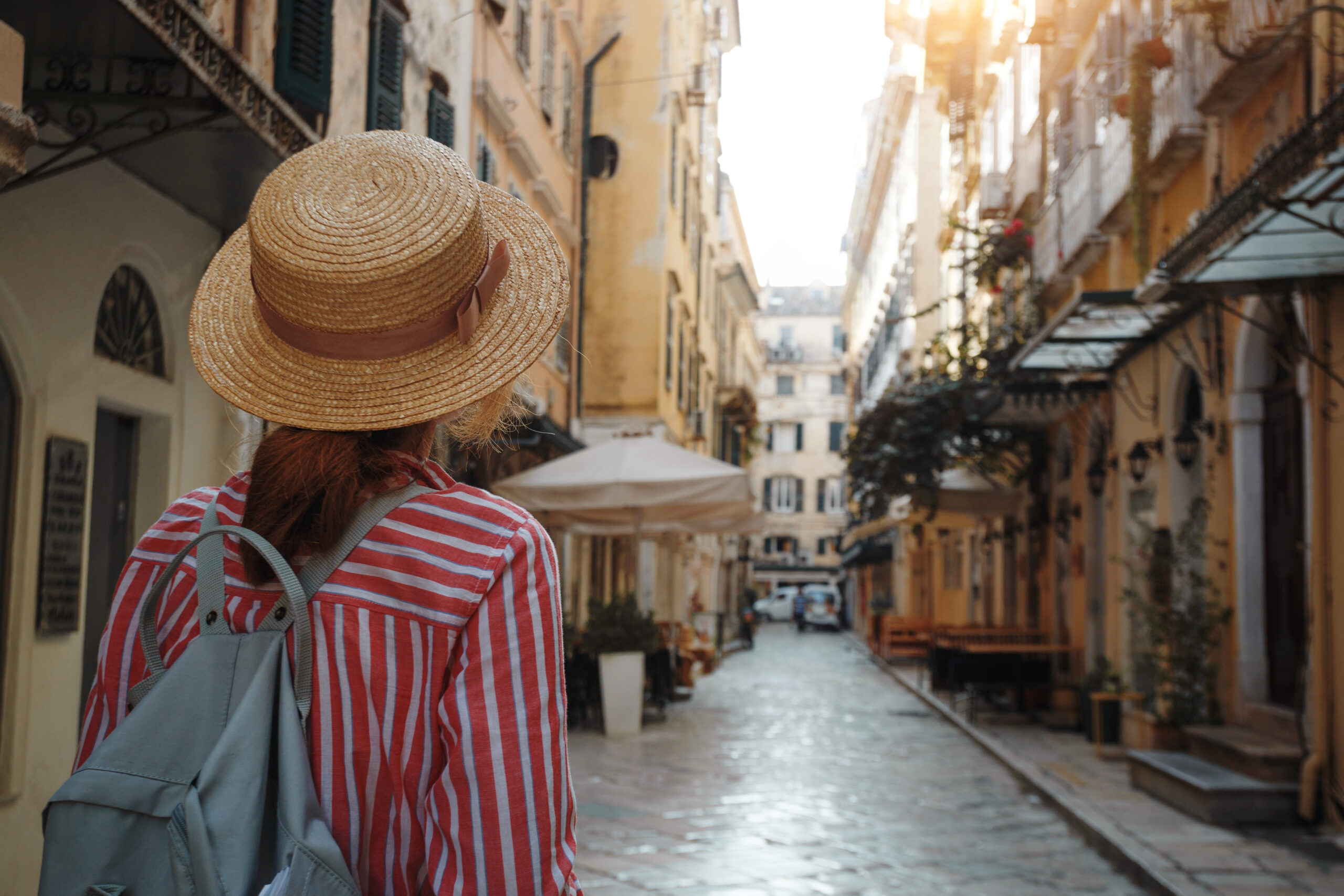 Learn Greek Hub A girl in a hat walks on the street of a Greek city
